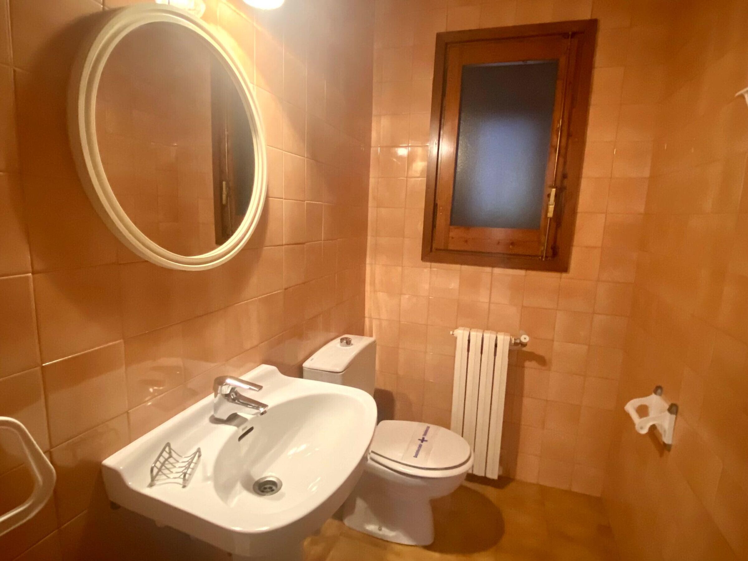 Un baño con lavamanos, inodoro y espejo.