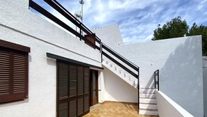Ein modernes Gebäude mit weißer Fassade, einer Holztreppe und einer gefliesten Terrasse.