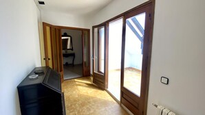 Ein enger Korridor mit einem schwarzen Schrank, einer Holztür, die auf einen Balkon führt, und einem Heizkörper an der Wand.