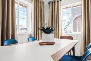 A conference room with a white table, blue chairs, a wooden tray, and a potted plant.