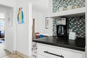 A modern kitchen with a coffee maker, a dining area with a table and chairs, and a view of the outside.