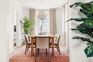 Un coin repas avec une table et des chaises en bois, un luminaire suspendu et une plante en pot.