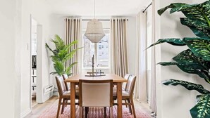 Een eethoek met een houten tafel en stoelen, een hanglamp en een vloerkleed met een patroon.