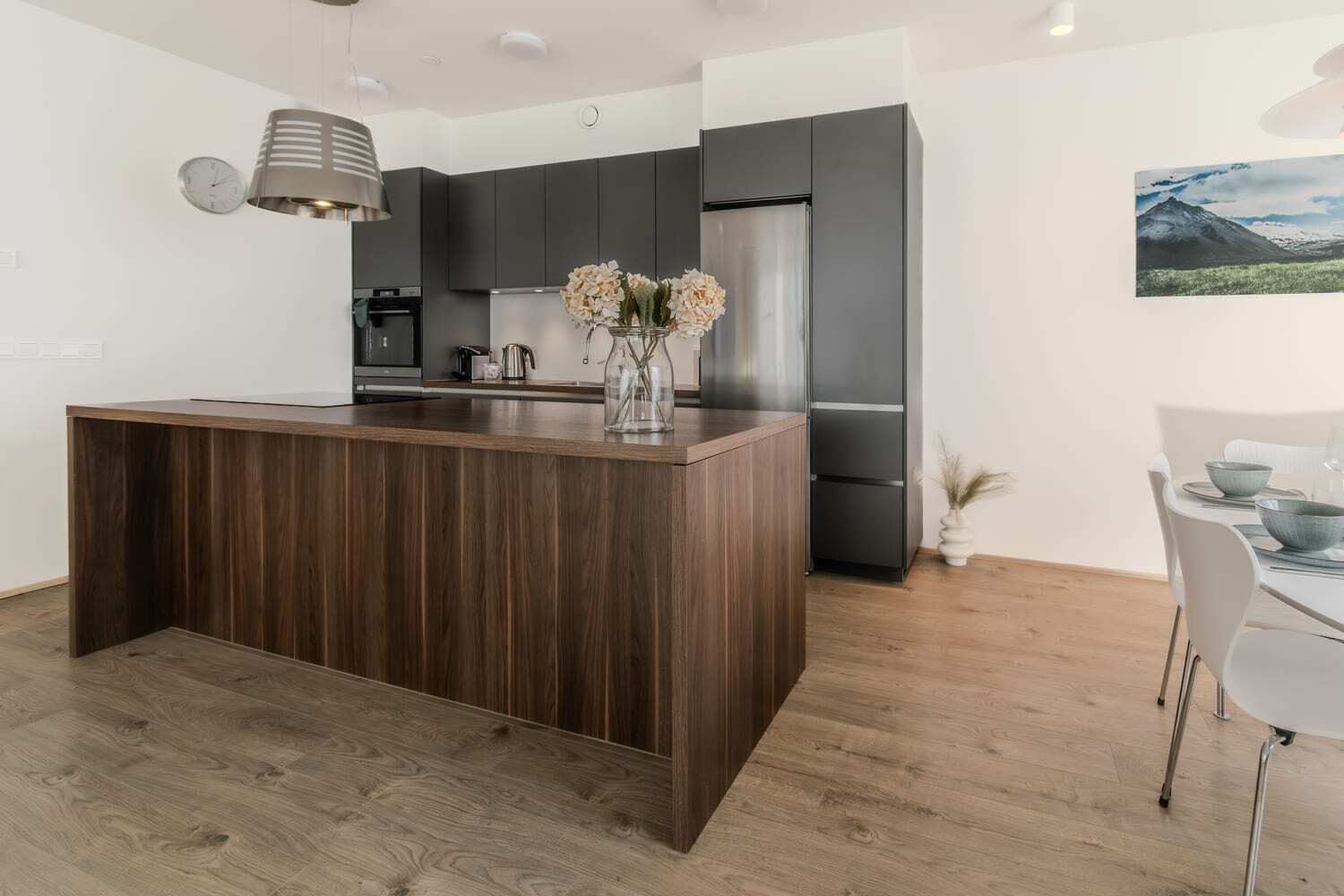 Una cucina moderna con mobili in legno scuro, un'isola centrale e un frigorifero in acciaio inossidabile.