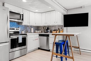 Une cuisine moderne avec des armoires blanches, une cuisinière en acier inoxydable et un dosseret de carrelage bleu et blanc.