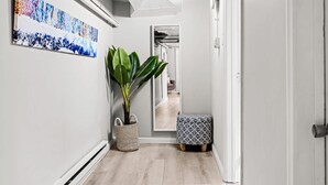A hallway with a large mirror, a potted plant, and a patterned ottoman. - Contemporary Studio Near Sloan's Lake | 30 Day (Denver)