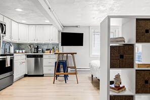 Una cocina moderna con armarios blancos, una mesa de madera y un televisor montado en la pared.