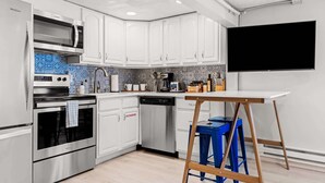 A modern kitchen with white cabinets, a stainless steel range, and a blue and white tiled backsplash. - Contemporary Studio Near Sloan's Lake | 30 Day (Denver)