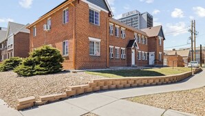 A two-story brick building with a gabled roof, a front entrance, and a small front yard with a tree and gravel. - Contemporary Studio Near Sloan's Lake | 30 Day (Denver)