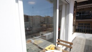 Un balcón con una mesa de madera, un plato de croissants, un vaso de zumo de naranja y una taza.