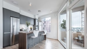 Una cocina moderna con una isla central, electrodomésticos de acero inoxidable y vistas de la ciudad a través de grandes ventanales.