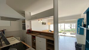 A modern kitchen with a built-in stove, wooden cabinets, and a dining area with a bench. - Ground floor apartment, 4 people, pool, beach 200 m, wifi (Fouras)