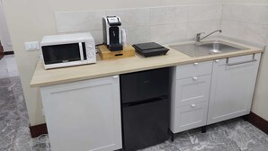 A compact kitchen with a microwave, coffee maker, and induction cooktop on a light-colored countertop.