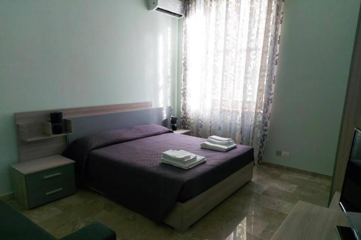 A bedroom with a bed, bedside table, and a desk.