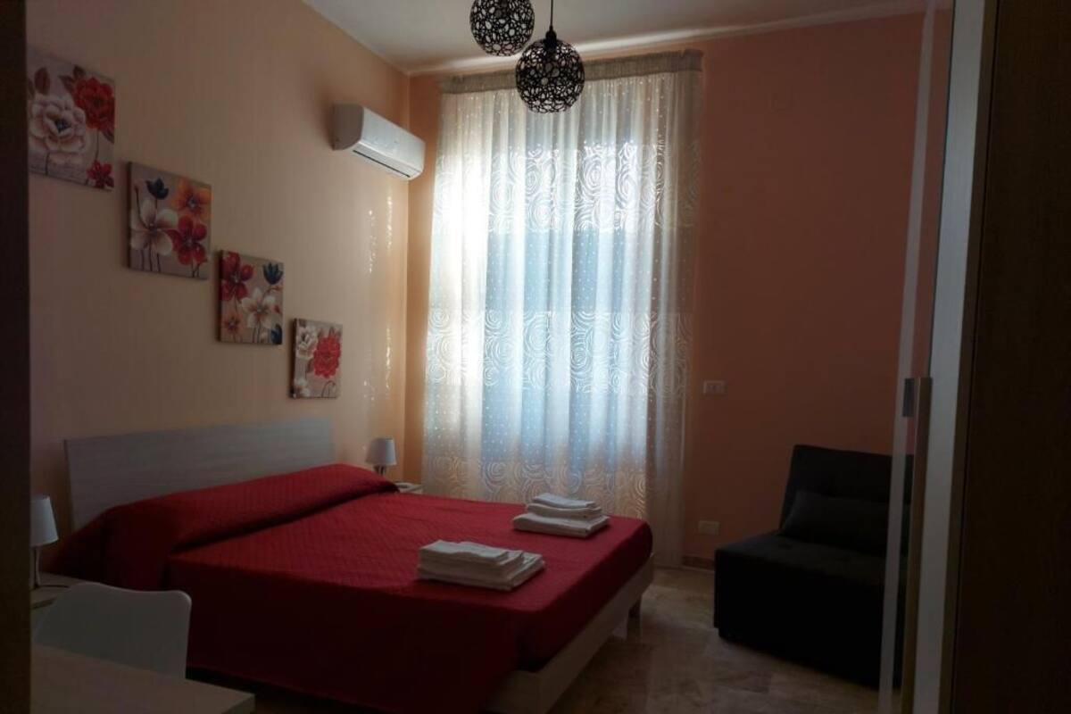 A bedroom with a bed, a chair, and artwork on the wall.