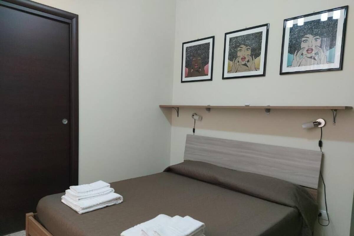 A bedroom with a bed, a wooden door, and three framed pictures on the wall.