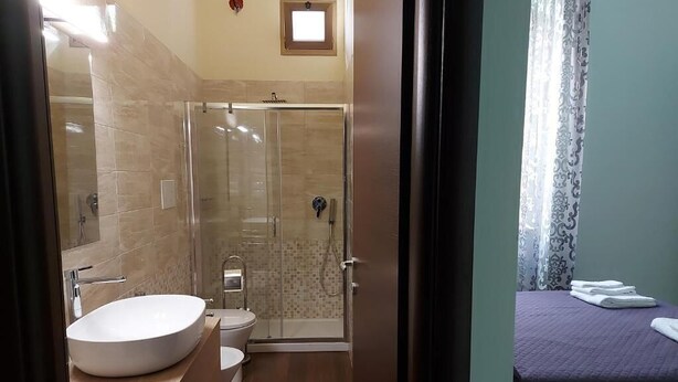 A bathroom with a large sink, toilet, and glass-enclosed shower. - Arte Mia b&b (Reggio Calabria)