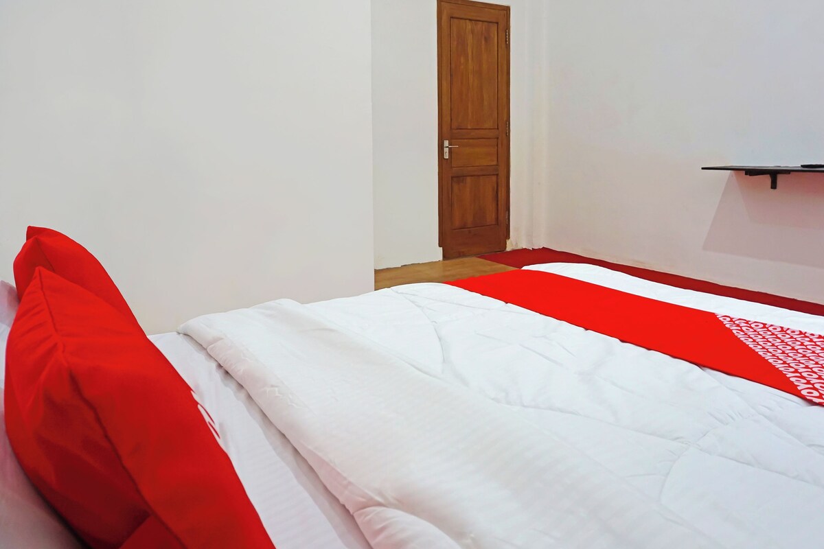 Une pièce avec un lit, une porte en bois et un mur blanc.
