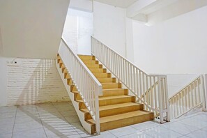 Un escalier avec des rampes blanches et des marches en bois menant à l’étage supérieur.
