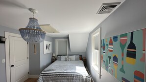 Quarto com cama, luminária de cristal, janela e parede com arte abstrata.