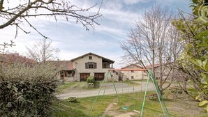 Ein zweistöckiges Haus mit sichtbarem Vorgarten, einer Schaukel und einem Garten.