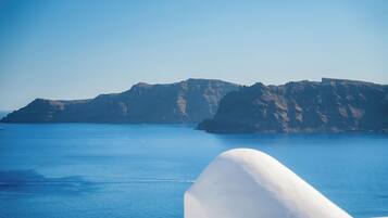 A coastal landscape with a clear blue sea and rocky cliffs.