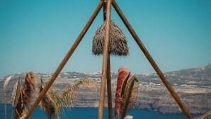 Escena en la playa con una mesa y sillas de madera, un sillón de tumba y una decoración con plumas.
