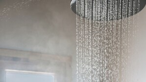Una persona duchándose con vista a un cuerpo de agua a través de una ventana.