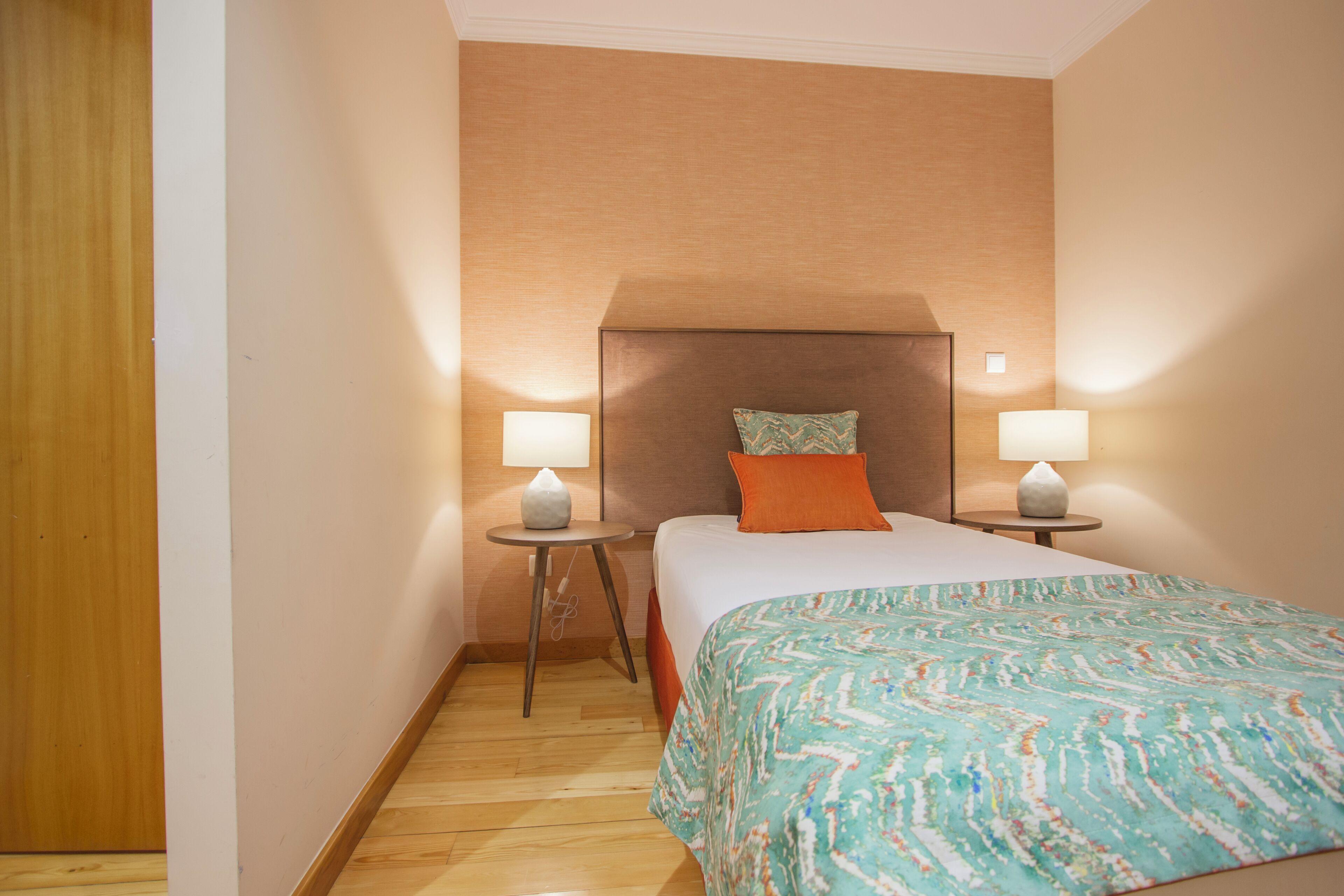 Une chambre d’hôtel avec un lit, deux lampes de chevet, une table de chevet et un plancher en bois.