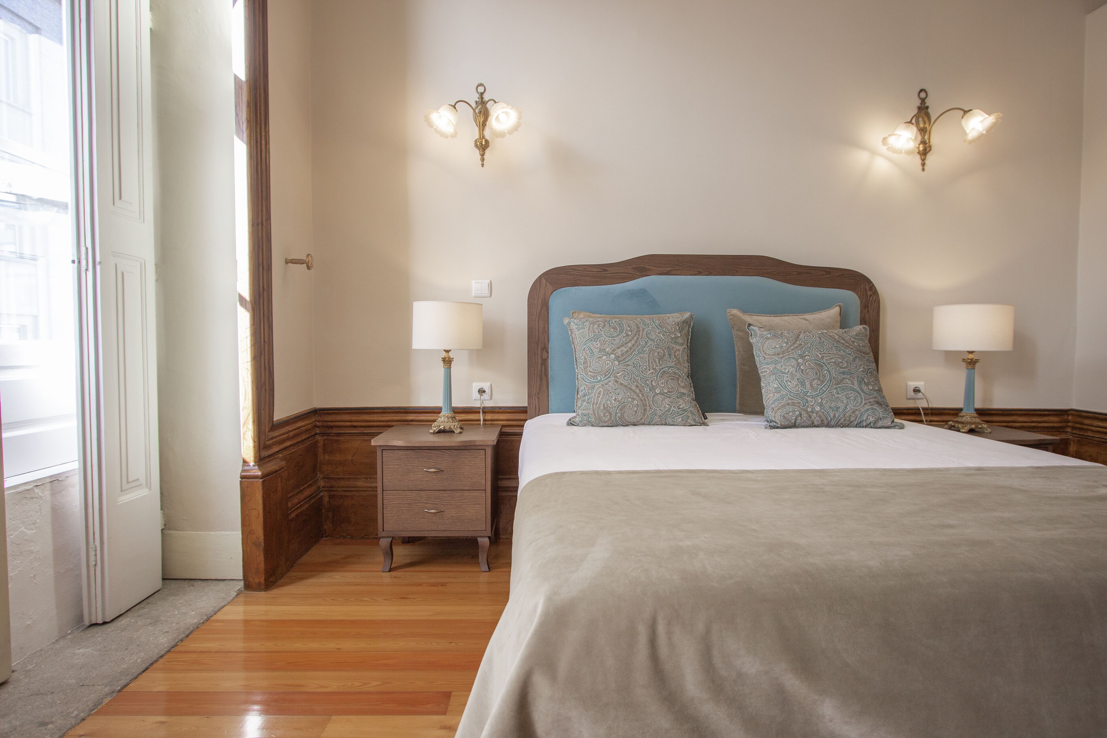 Une chambre à coucher avec un grand lit, deux tables de chevet et des lampes fixées au mur.