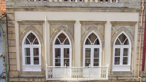 Un bâtiment doté de trois fenêtres en arc et d’un balcon avec des balustrades blanches.
