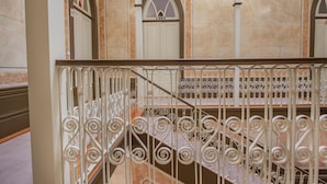 Un escalier orné de rampes blanches et un mur de marbre agrémenté d’arcades.