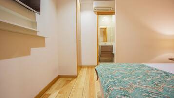 Een slaapkamer met een bed, een houten vloer, een inbouwkast en een deur naar een badkamer.