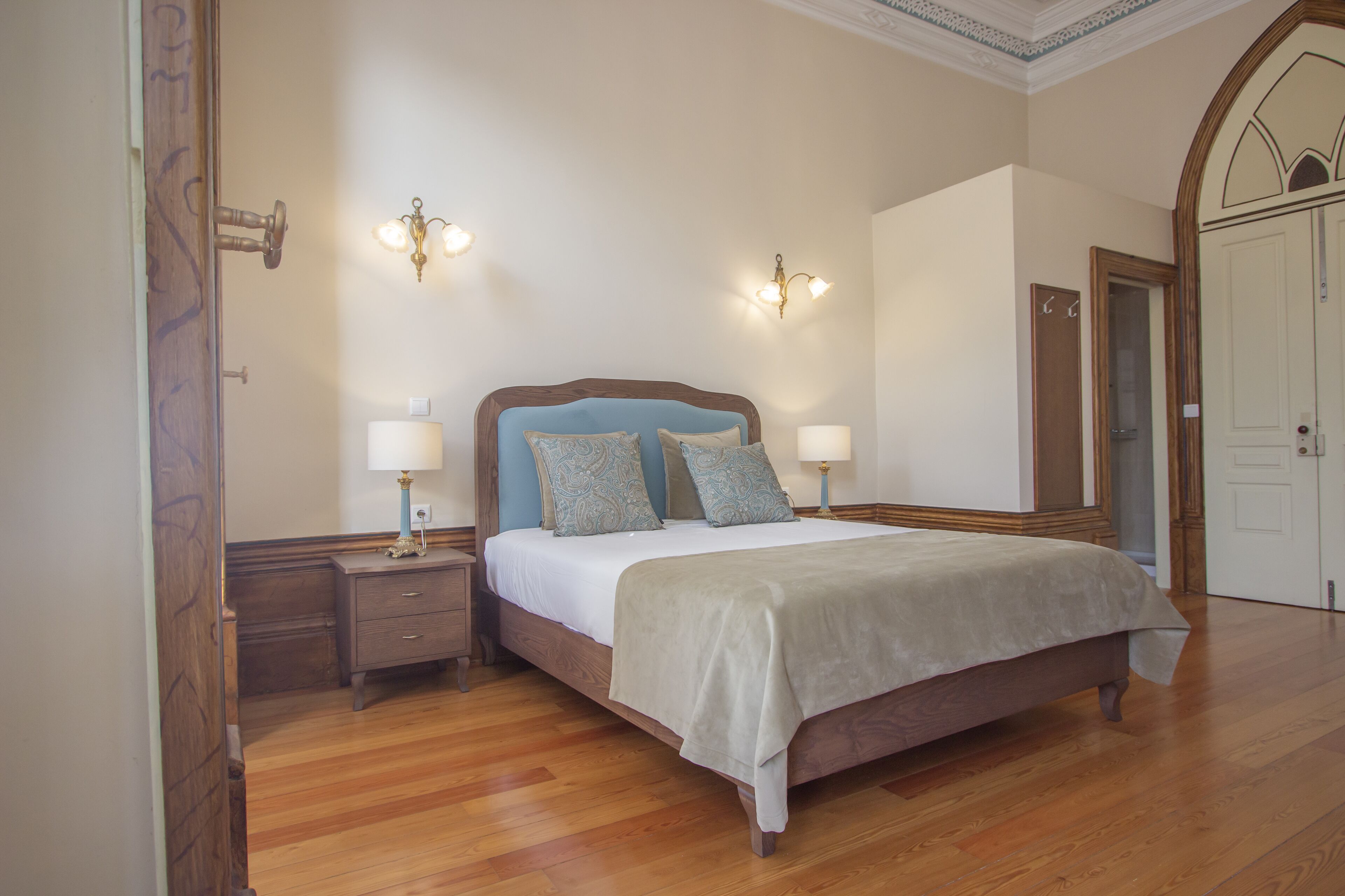 Une chambre à coucher avec un lit en bois, deux tables de chevet avec des lampes et une porte dotée d’un miroir.
