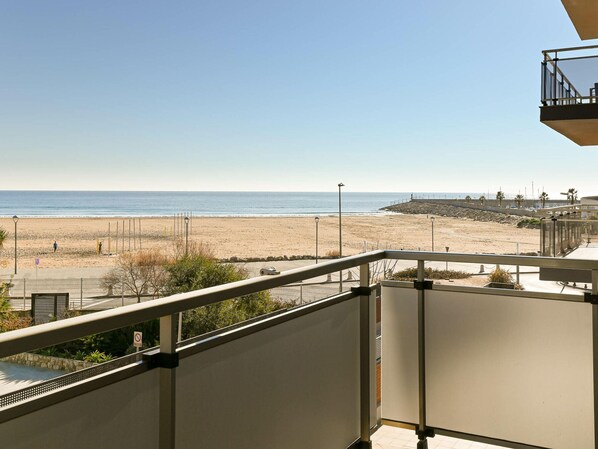 A balcony with a view of a beach and the ocean.