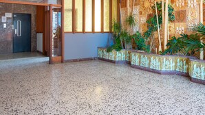 Eine geräumige Lobby mit einem gemusterten Boden, ein Empfangsbereich mit einer Wandausstattung und eine Tür zu einem weiteren Raum.
