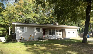 A single-story house with a front porch, a garage, and a yard. - Dog Friendly with Trail Access to Bike Trails, Lakes, Waterfalls, MTB & Golf (Bella Vista)