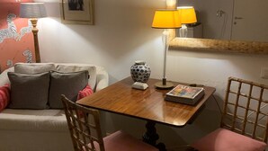 A cozy living room with a wooden table, two chairs, a sofa, and a lamp. - Small Luxury Apartment (Venezia)