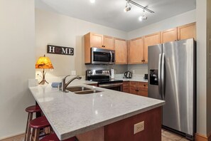 A modern kitchen with granite countertops, stainless steel appliances, wooden cabinets, and a marble island with bar stools. - 1 Minute Walk to the Super Bee Chair! Enjoy the Best of Copper from this Beautif (Frisco)