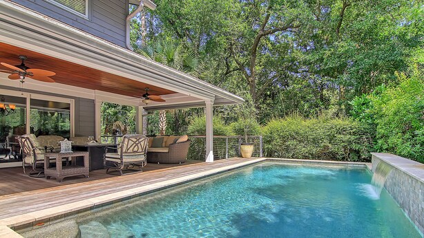 A swimming pool with a wooden deck, outdoor furniture, and a waterfall feature. - New rental property, The Oasis (Kiawah Island)