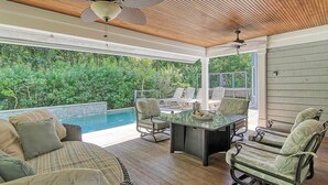A covered outdoor area with a pool, lounge chairs, and a table. - New rental property, The Oasis (Kiawah Island)