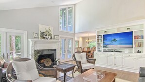 A spacious living room with a fireplace, comfortable seating, a large flat-screen TV, and a bookshelf. - New rental property, The Oasis (Kiawah Island)