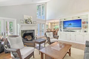 A spacious living room with a fireplace, comfortable seating, a large flat-screen TV, and a bookshelf. - New rental property, The Oasis (Kiawah Island)