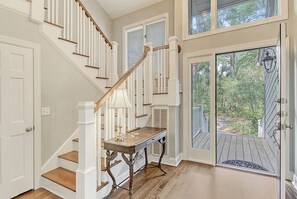A staircase with white railings and wooden steps, a small table with a lamp, and a door leading to a wooden deck. - New rental property, The Oasis (Kiawah Island)