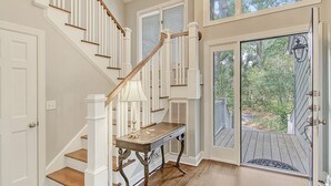 A staircase with white railings and wooden steps, a small table with a lamp, and a door leading to a wooden deck. - New rental property, The Oasis (Kiawah Island)