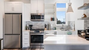 A modern kitchen with white cabinets, stainless steel appliances, and a large island.
