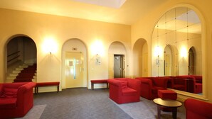 A lobby with red seating, a staircase, and a large mirror reflecting the space. - La Bourboule: T2 bis Apartment for 5 ppl, 49m², with Wifi (La Bourboule)