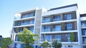 A multi-story residential building with balconies, large windows, and a modern architectural design.