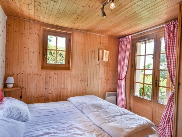 A wooden-paneled room with a bed, a window, and a mirror. - Chalet Papillon - 8 Pers - Proche Lac des Ecoles et Pistes de Ski des Chavannes (Les Gets)