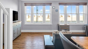 A spacious living room with large windows, a flat-screen TV, and a cozy seating area.